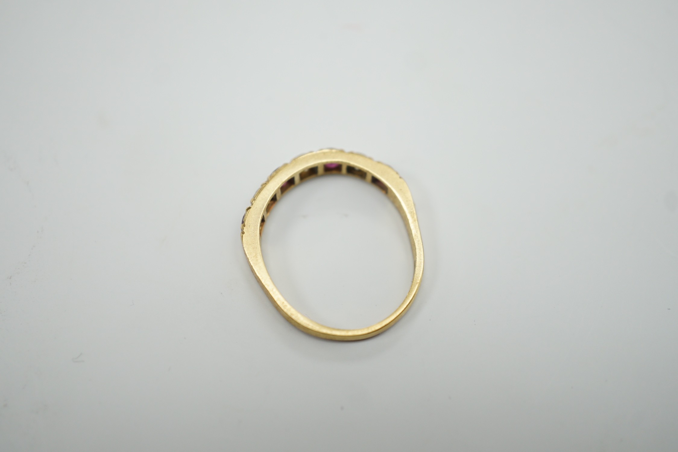 A modern 18ct gold, four stone ruby and three stone diamond set half hoop ring, size L/M